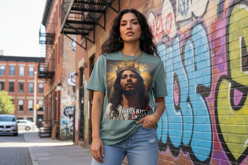 Teal t-shirt with a graphic of a crowned Hispanic Jesus and 'He is Risen' text on a white background