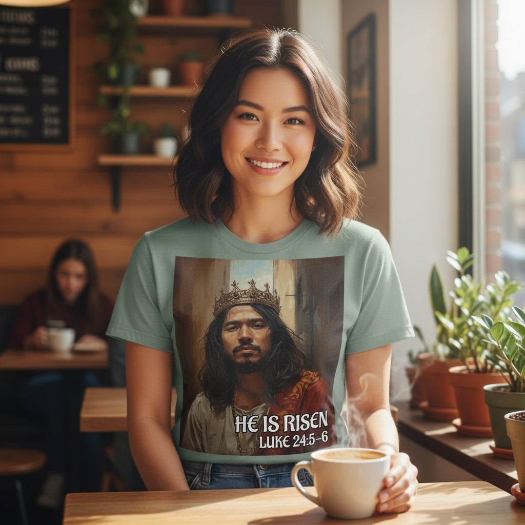 Woman wearing a t-shirt with a religious design of a crowned Asian Jesus, sitting at a table in a cafe.