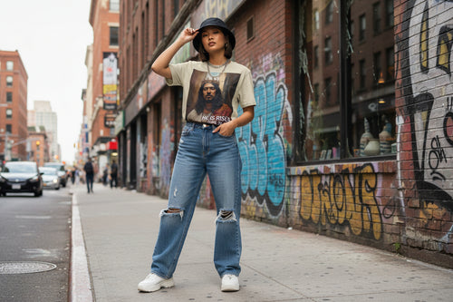 Person wearing a graphic t-shirt of Asian Jesus and jeans standing on a city street with graffiti.