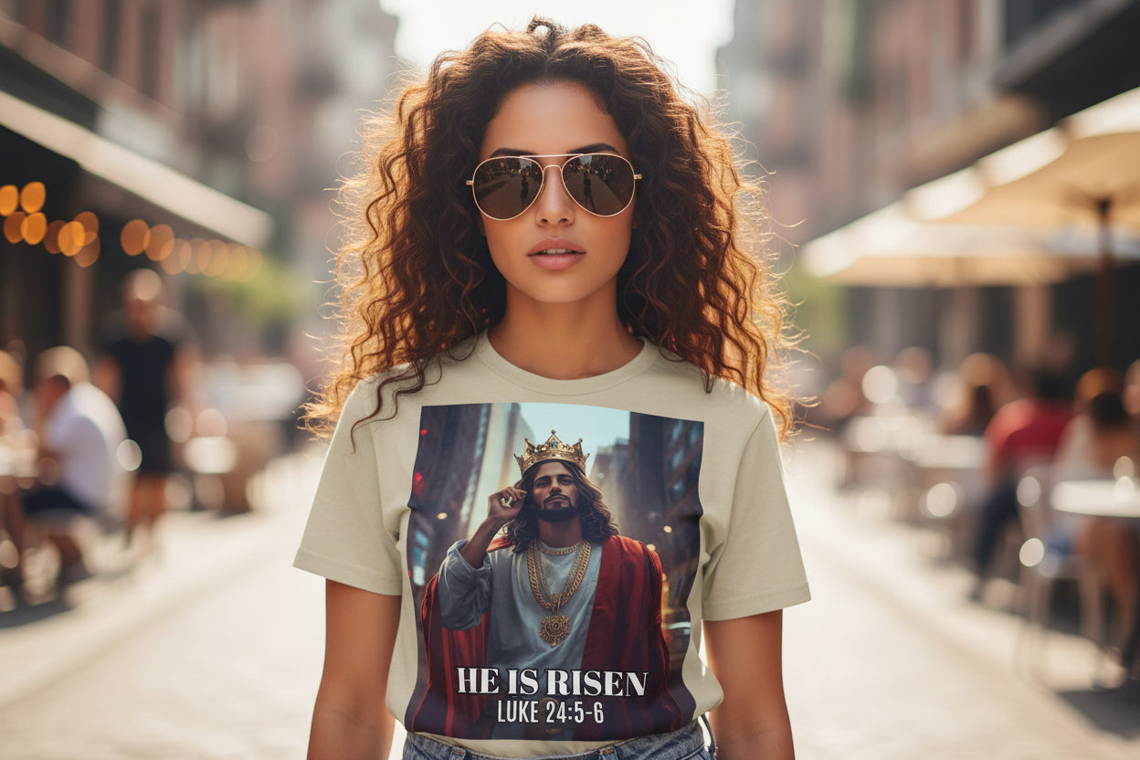 T-shirt with a graphic of a robed Latino Jesus with a crown and 'He is Risen' text on a beige background