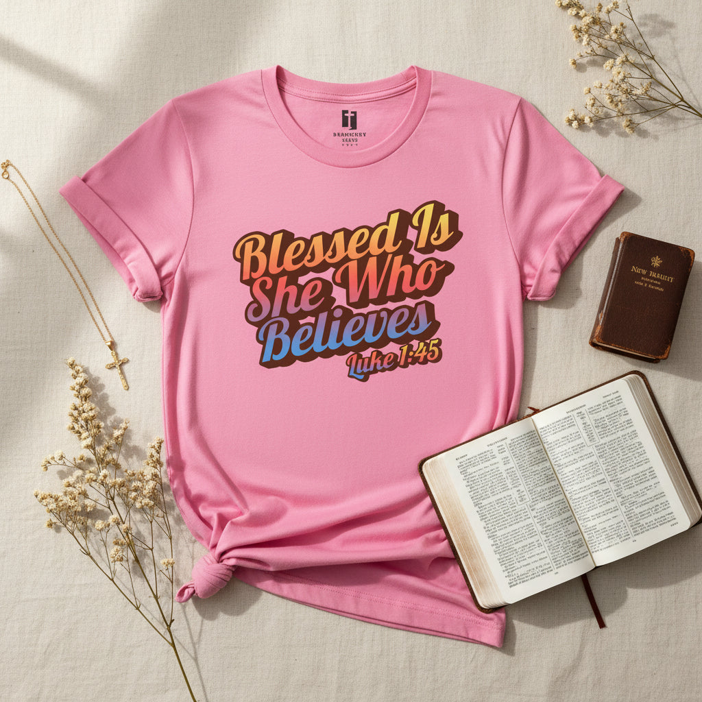 Pink t-shirt with 'Blessed Is She Who Believes' text on a white background
