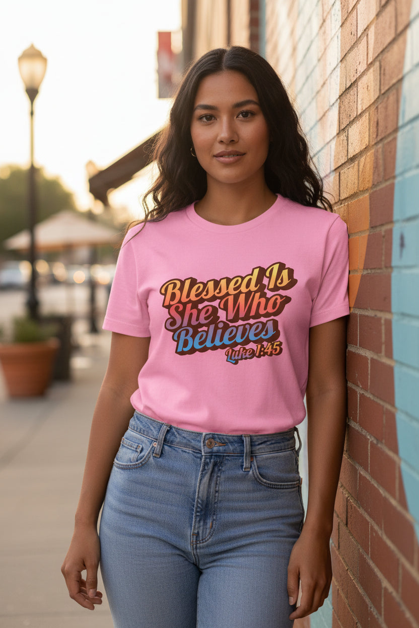 Woman wearing a pink t-shirt with 'Blessed Is She Who Believes' text on a white background