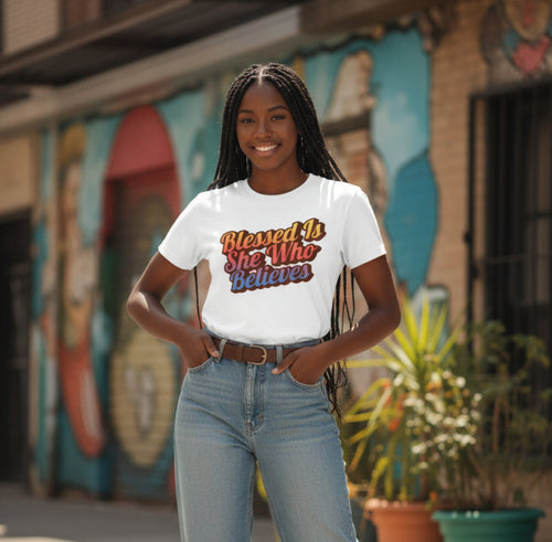 Woman wearing a white t-shirt with a motivational quote in front of a colorful mural.
