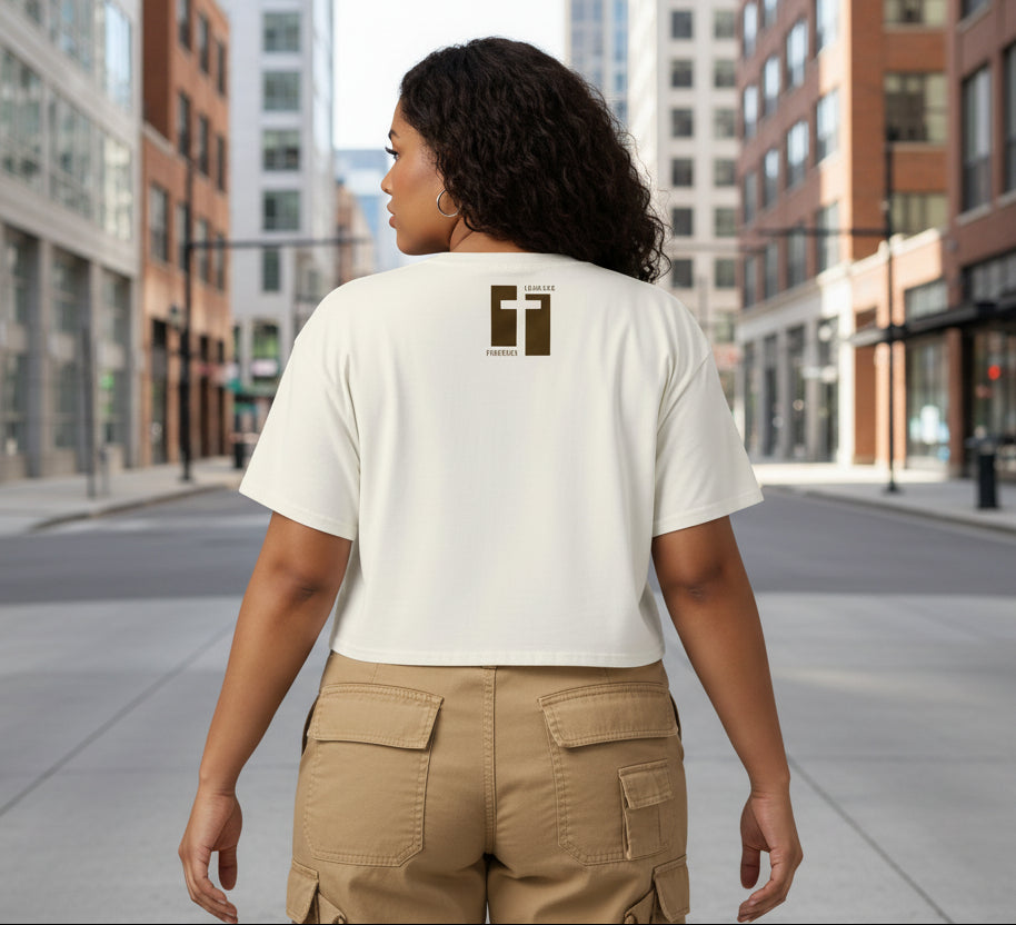 Ecru cropped t-shirt with a brown cross design on the back against a gray background